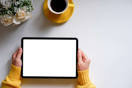 A woman using a blank screen tablet With coffee mugs and flower potsの写真素材