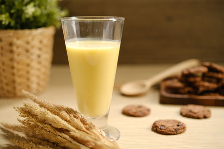 Tasty fresh corn milk in glass and cobs on white wooden table.の写真素材
