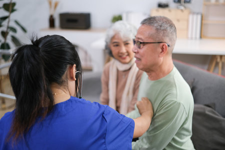 Attentive doctor or healthcare worker giving professional advice to senior couple during home visit.の写真素材