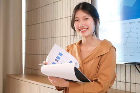 Image of young asian woman, company worker smiling and holding documents.の写真素材