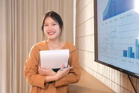 Image of young asian woman, company worker smiling and holding documents.の写真素材