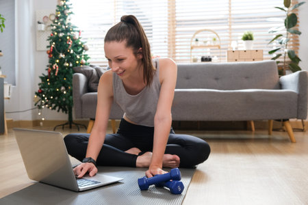 Workout at home. Attractive girl does home workout watching video tutorial on a laptop..の写真素材