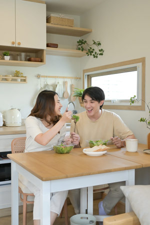 A man and woman are eating together in a kitchen..