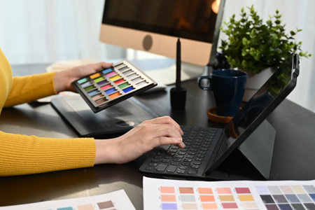 A woman is sitting at a desk with a yellow shirt on and is working on a color palette..の写真素材