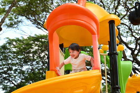 A young child is playing on a yellow and orange play structure. The child is smiling and he is enjoying the activity.の写真素材