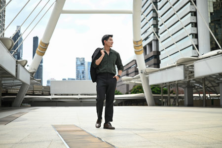 A man is walking down a city street. The scene is set in a modern city with tall buildings in the background.の写真素材
