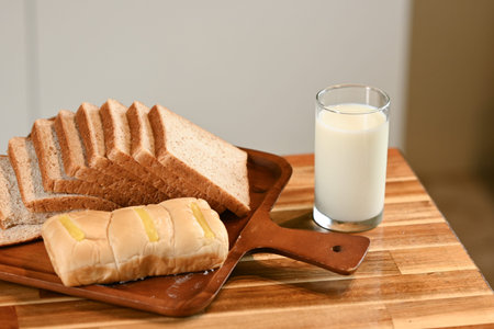 Freshly baked bread and a glass of milk on a kitchen table.