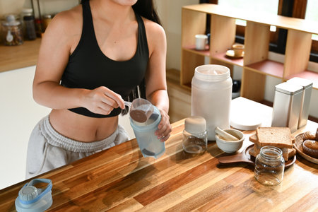 A woman is making a protein shakes in a kitchen. She is smiling and she is enjoying the process.の写真素材