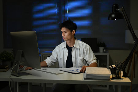 Businessman working overtime at his desk late at night.の写真素材