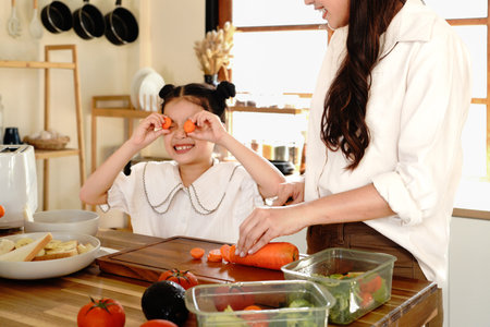 Mother and happy girl Make a salad in kitchen as a family with a young kid learning recipe at home.