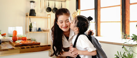 daughter kissing Mother on forehead before school in modern kitchen.の写真素材