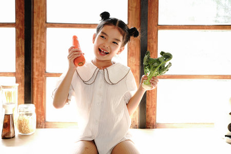 little girl sing while in the kitchen, using carrots and broccoli as microphones..の写真素材