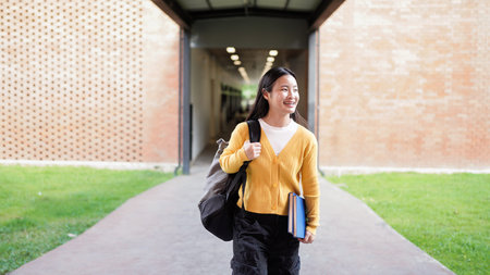 Portrait of smiling high school student with backpack and planner standing on school campus.の写真素材