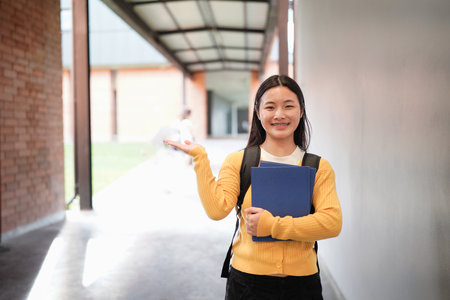 Portrait of smiling high school student with backpack and planner standing on school campus.の写真素材
