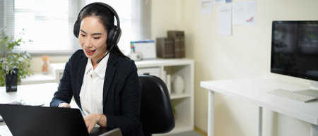 A woman wearing headphones is talking on a laptop.