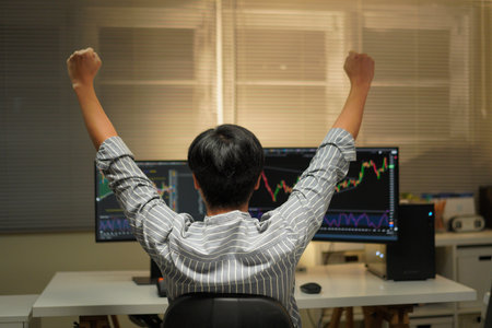 business man congratulations stock trader sitting at a desk in front of computer monitors.の写真素材