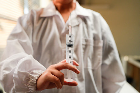Woman doctor wearing uniform holding syringe in clinic.の写真素材