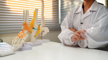 Woman doctor wearing uniform holding syringe in clinic.の写真素材