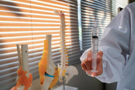 Woman doctor wearing uniform holding syringe in clinic.