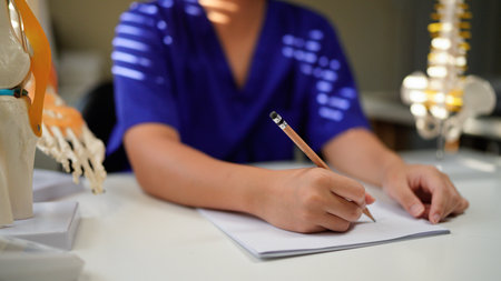Doctor taking notes in office with spine model for diagnosis.の写真素材