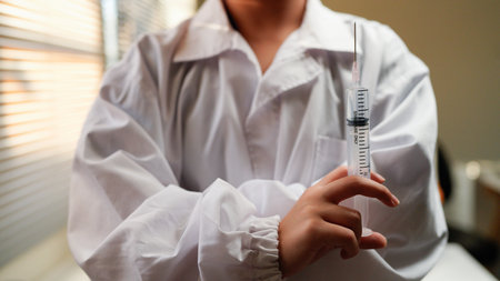 Woman doctor wearing uniform holding syringe in clinic.の写真素材