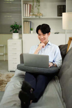 man freelancer working using laptop computer sitting on couch at home interior, guy surfing Internet, using modern technologies, free space.の写真素材
