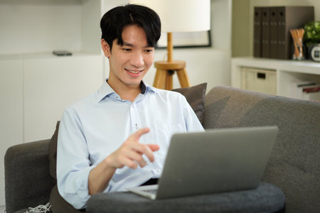 man freelancer working using laptop computer sitting on couch at home interior, guy surfing Internet, using modern technologies, free space.の写真素材