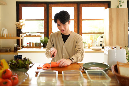 A man is cutting a carrot on a wooden cutting board..の写真素材
