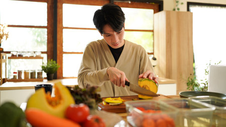 Man carving a pumpkin with a knife on a wooden cutting board.の写真素材