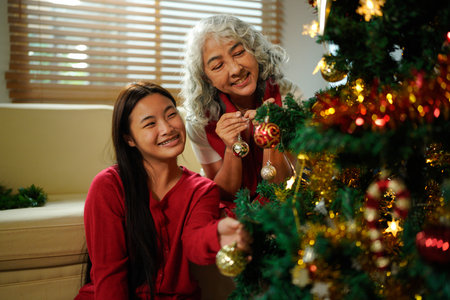 Grandmother And Granddaughter Decorating Christmas Tree At Home Together.の写真素材