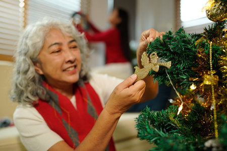 Grandmother And Granddaughter Decorating Christmas Tree At Home Together.の写真素材