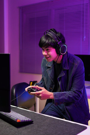 Gamer playing video game wearing headphones in a dark room.