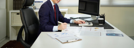 businessman hand working with finances about cost and calculator and computer on desk in modern office.の写真素材
