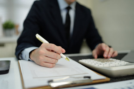 businessman hand working with finances about cost and calculator and computer on desk in modern office.の写真素材