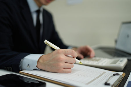 businessman hand working with finances about cost and calculator and computer on desk in modern office.の写真素材