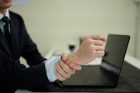 Businessman suffering from wrist pain in office.の写真素材
