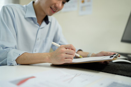 man holding clipboard with checklist employee workplace is reviewing documents in office.の写真素材