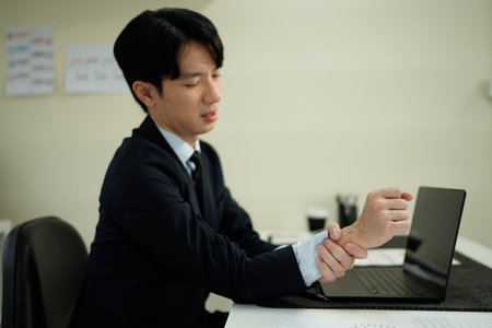 Businessman suffering from wrist pain in office.の写真素材