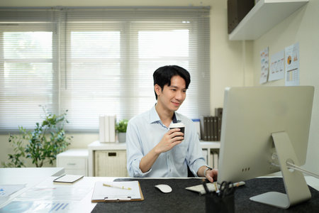 Software developer drinking coffee while working with computer in the modern startup office..の写真素材