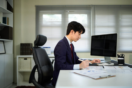 businessman hand working with finances about cost and calculator and computer on desk in modern office.の写真素材