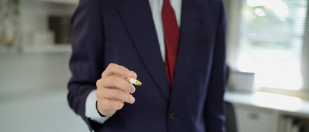 close up hand businessman stand in black suit pointing a pen at front camera and copy space in office.の写真素材