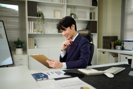 man holding clipboard with checklist employee workplace is reviewing documents in office.の写真素材