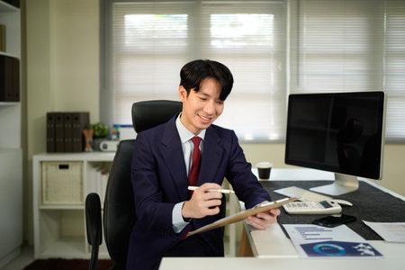 man holding clipboard with checklist employee workplace is reviewing documents in office.の写真素材