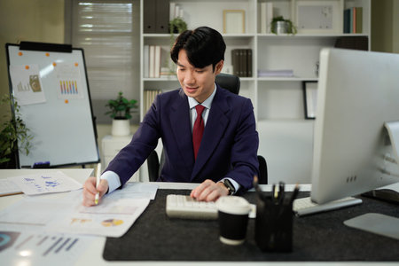 businessman hand working with finances about cost and calculator and computer on desk in modern office.の写真素材