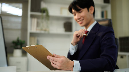 man holding clipboard with checklist employee workplace is reviewing documents in office.の写真素材