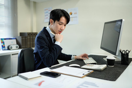 Business man, thinking and computer at desk in office for online research, reading email or report. Male entrepreneur person with internet connection for feedback, review and focus on project.の写真素材