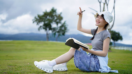 woman, writing and book in park, thinking and relax by tree, grass or sunshine for peace. Girl,...