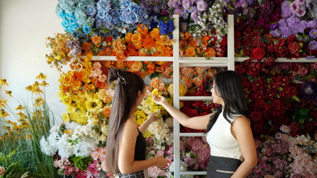 Two female florist partners discuss bouquet arrangement design in online flower shop with fresh flowers With copy space for text.の写真素材
