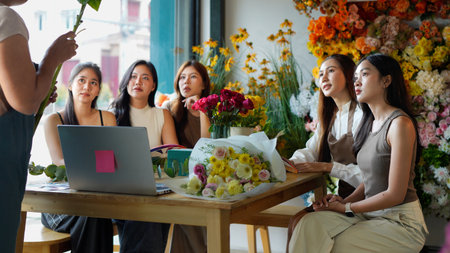 Diverse group of young people arranging flowers in florists workshop while attending class on floral art.の写真素材