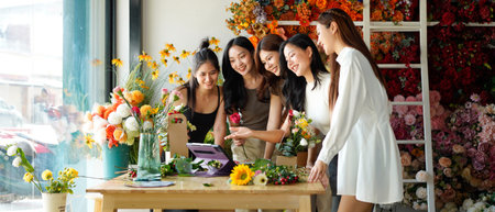 Diverse group of young people arranging flowers in florists workshop while attending class on floral art.の写真素材